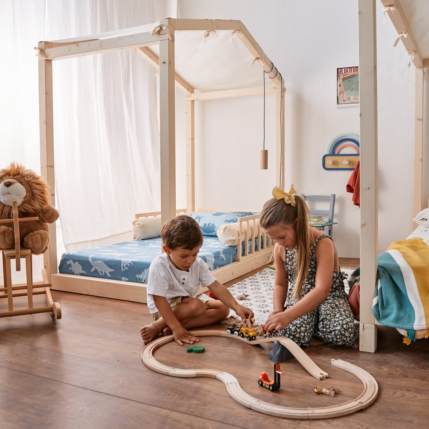 bambini giocano in una cameretta con due letti montessori con baldacchino coperto con telino colore naturale