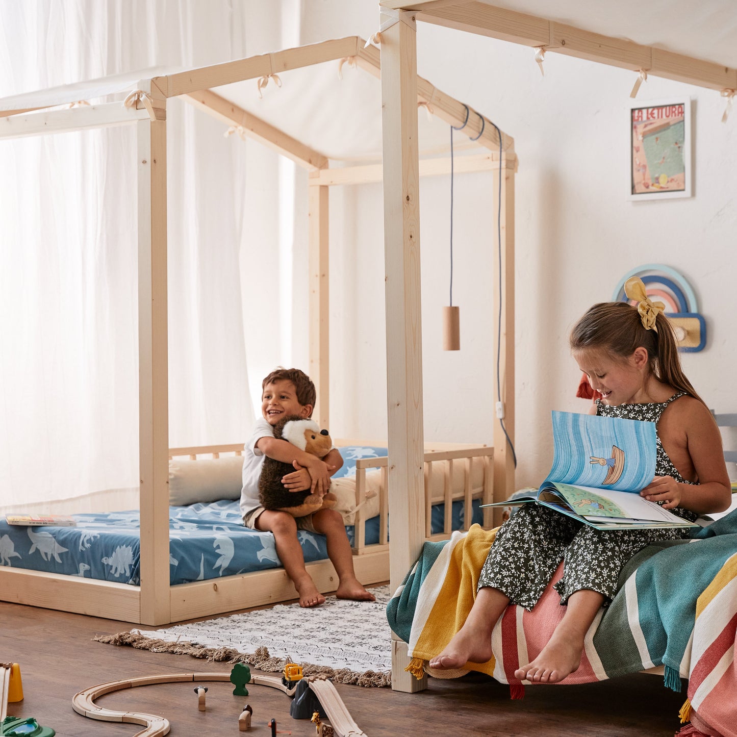 bimbi giocano seduti su lettino Montessoriano in legno naturale