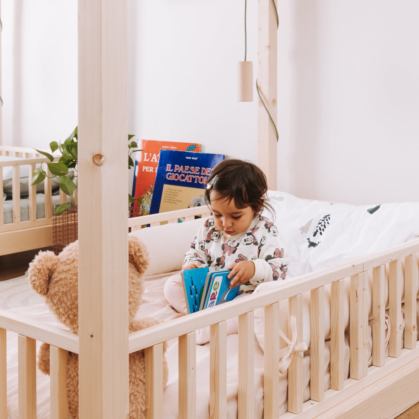 bambina piccola seduta su lettino montessoriano in legno naturale nabè